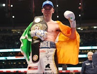 a boxer holding an irish flag in front of a boxing ring