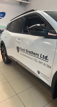 a white nissan c-ruise is parked in a showroom