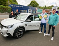 three men standing next to a white car