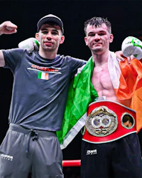 two boxers posing with their belts in the ring