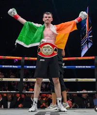a boxer is holding up an irish flag in the ring
